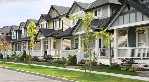 A row of Craftsman-style homes with a sidewalk and road out front. 