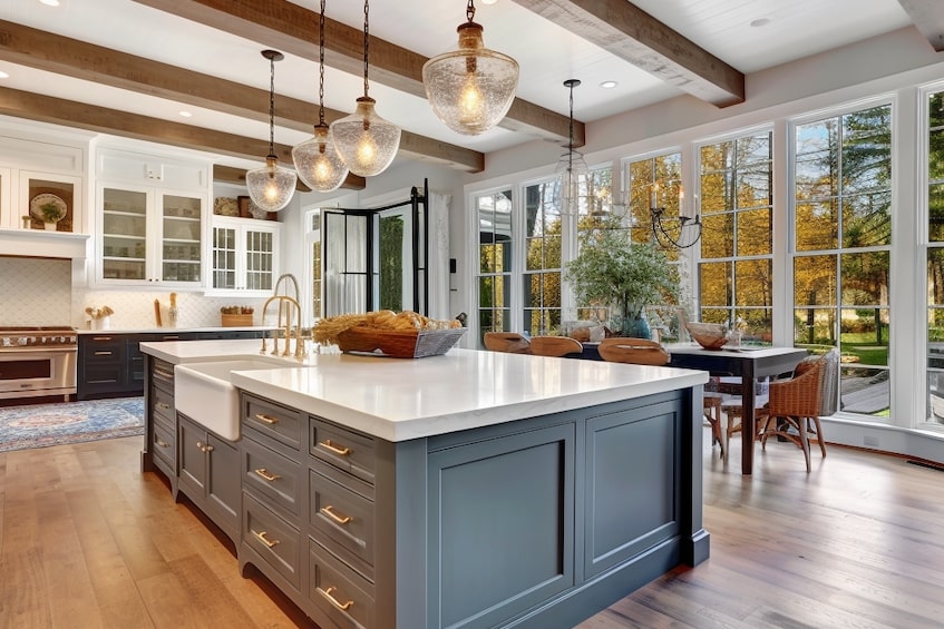 A luxurious kitchen with a sunken sink and paneled windows with a view outdoors. 