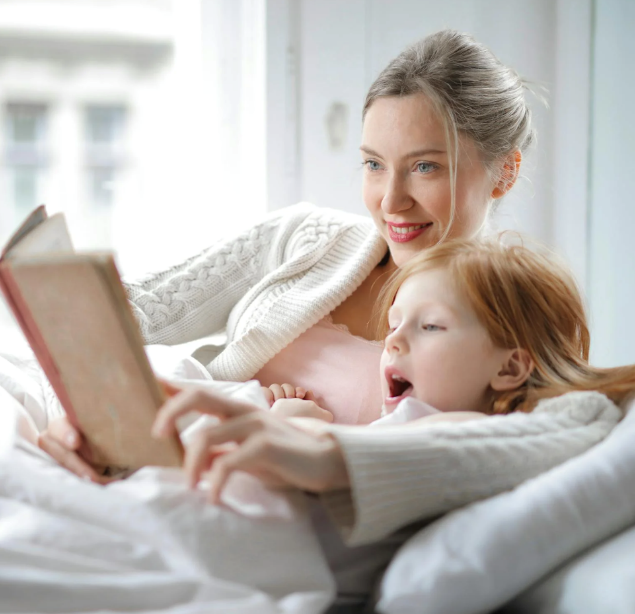 A mom reading a book to her little girl.