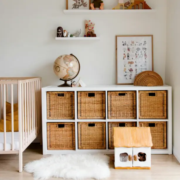 A storage unit with wicker baskets, two shelves above it, a fur rug, and a crib.