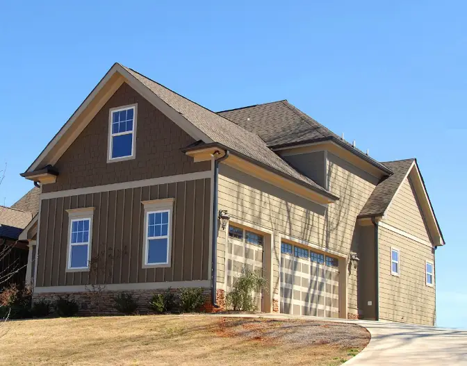 A large house on top of a hill with a three-car garage.