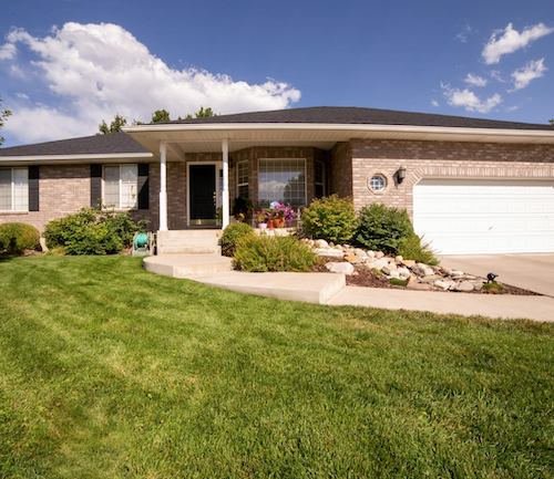 A one-story home with a one-car garage and a green front yard.