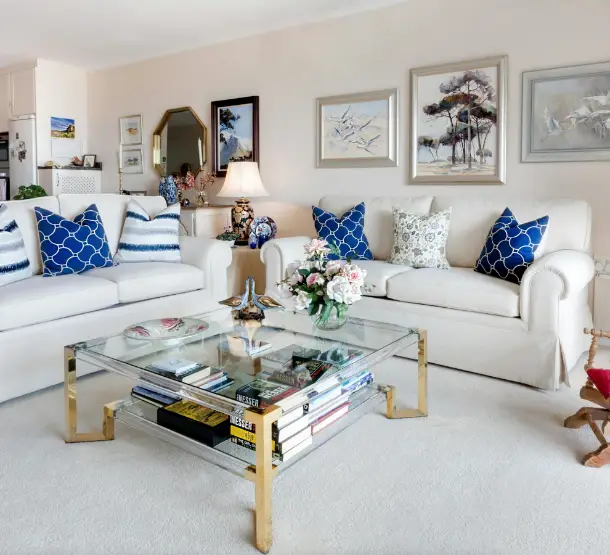 Living room with two white sofas and a glass coffee table.
