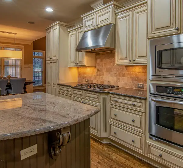 A custom kitchen with double ovens, a stainless steel stove hood, and recessed lighting