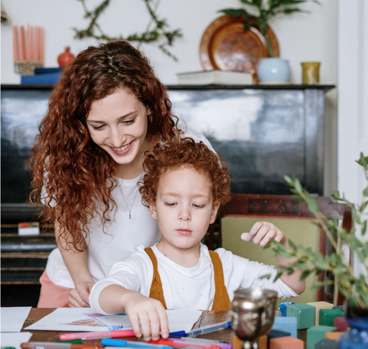 A picture of a mother overlooking her daughter drawing.