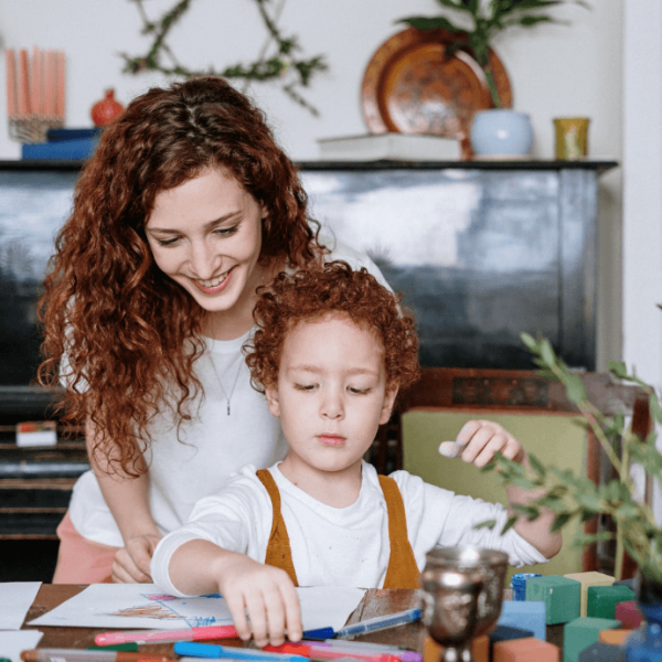 A picture of a mother overlooking her daughter drawing.