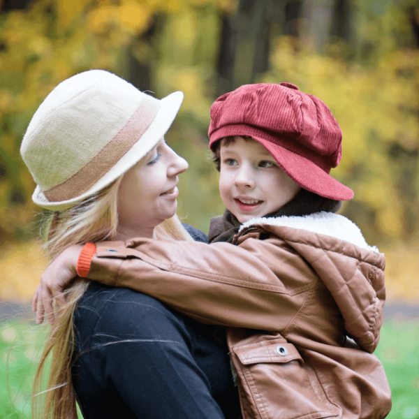 A mother holding her son. Both are smiling.