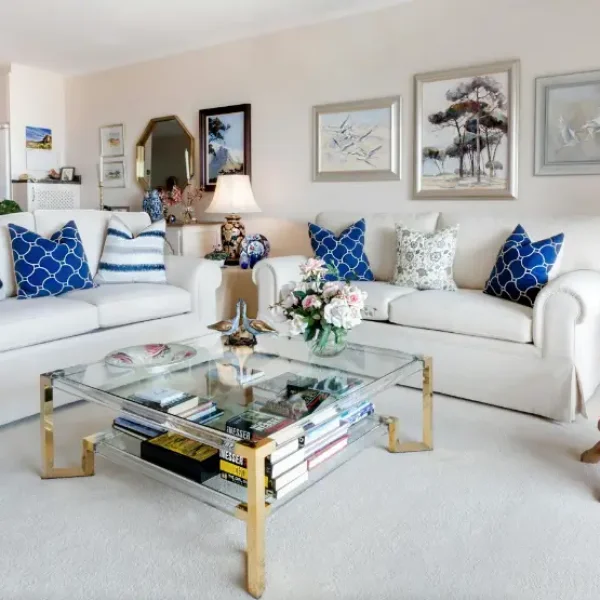 Living room with two white sofas and a glass coffee table.