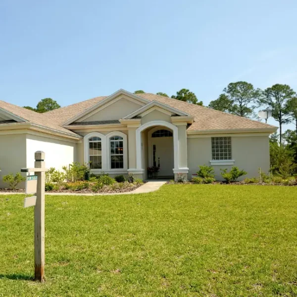 A one-story home with a for sale sign in the yard.