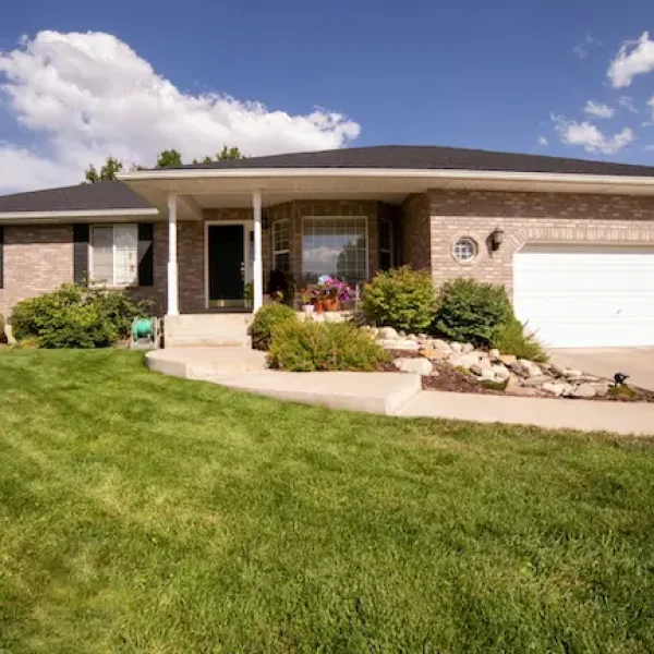 A one-story home with a one-car garage and a green front yard.