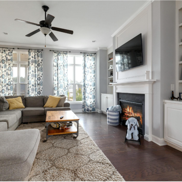 A living room with large windows, a fireplace, and a TV.